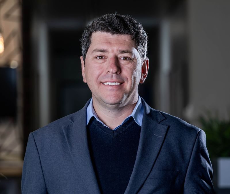 Portrait of Ian Erlank, Chief Treasurer at Bank Windhoek, wearing a blue blazer and sweater in an office setting.